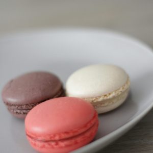 A delicious assortment of chocolate, vanilla, and raspberry macarons on a plate.